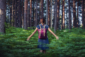 A woman feels plants as she walks through a forest. Learn how EMDR therapy in Phoenix, AZ can offer support in overcoming trauma. We offer trauma counseling Phoenix, AZ and other services.